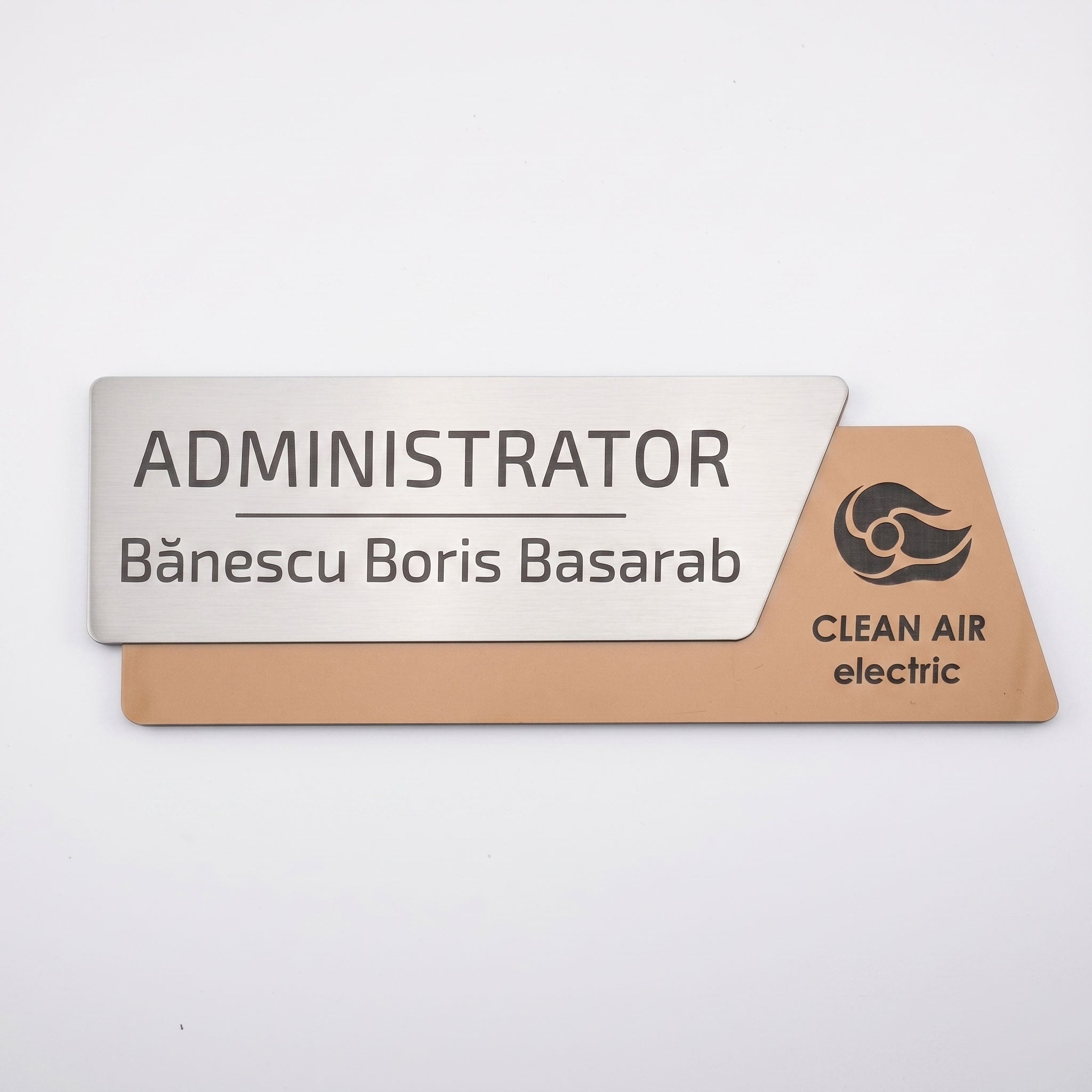 Plăcuță premium de identificare pentru birou formată din două elemente, cu fața metalică argintiu periat gravată cu textul „ADMINISTRATOR Bănescu Boris Basarab” și o bază asimetrică cu textură de lemn maro deschis și logo-ul Clean Air electric, pe fundal alb.