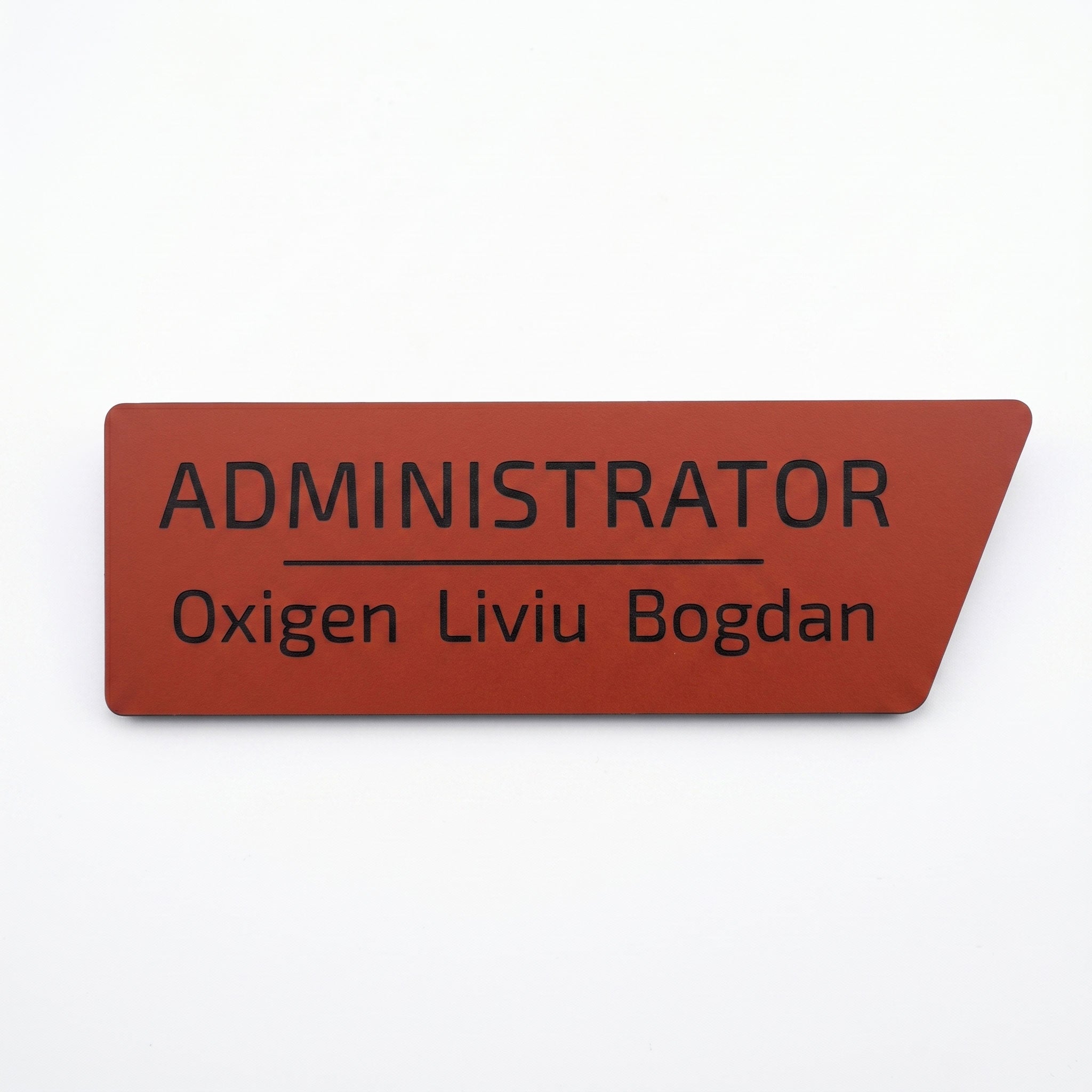 Plăcuță de identificare simplă pentru birou din acril roșu închis mat, cu tăietură asimetrică pe colțul din dreapta, gravată cu textul „ADMINISTRATOR Oxigen Liviu Bogdan”, pe fundal alb.