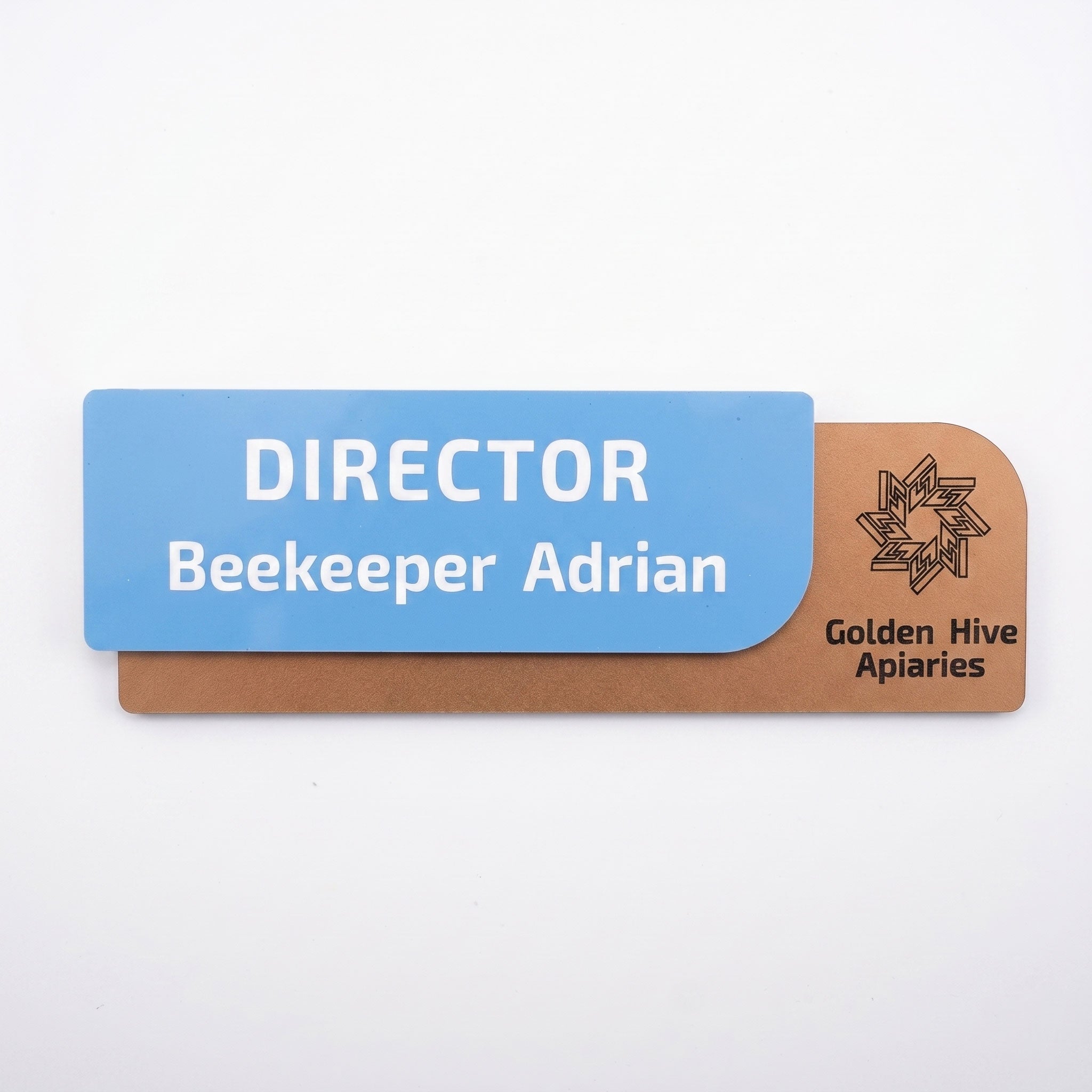 Vedere frontală a plăcuței de identificare complete, prezentând piesa albastră cu textul „DIRECTOR Beekeeper Adrian” fixată pe baza neagră cu logo-ul companiei, pe fundal alb.