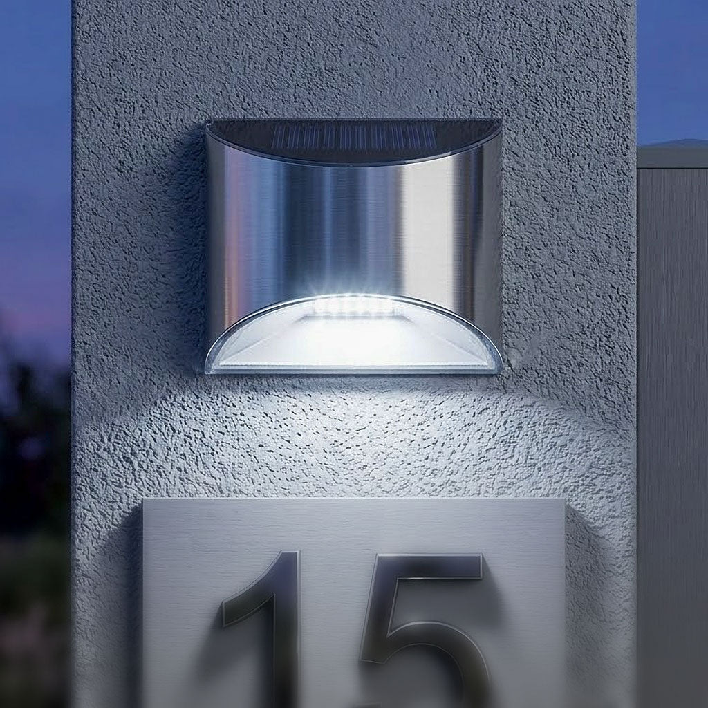Dispozitiv de iluminat solar premium cu carcasa din inox, instalat deasupra unui numar de casa 15 intr-o curte interioara. Lampa este orientata in jos si proiecteaza o lumina clara pe placuta de identificare.