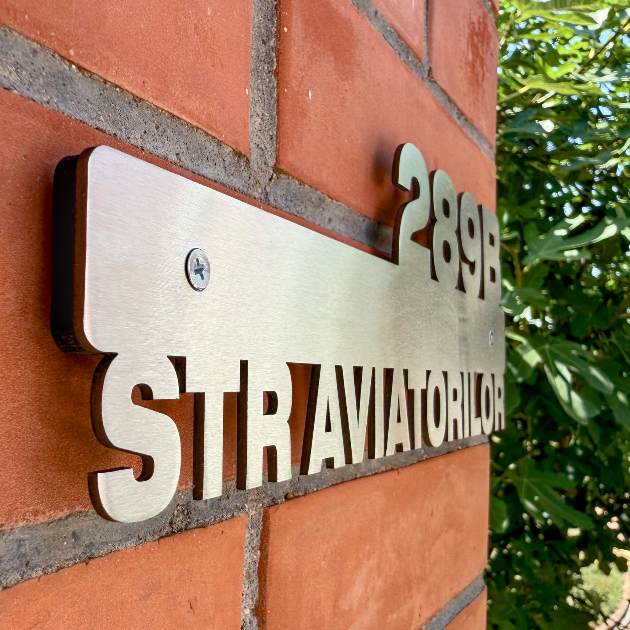 Detalii număr de casă decupat din inox, montat pe cărămidă cu distanțieri.