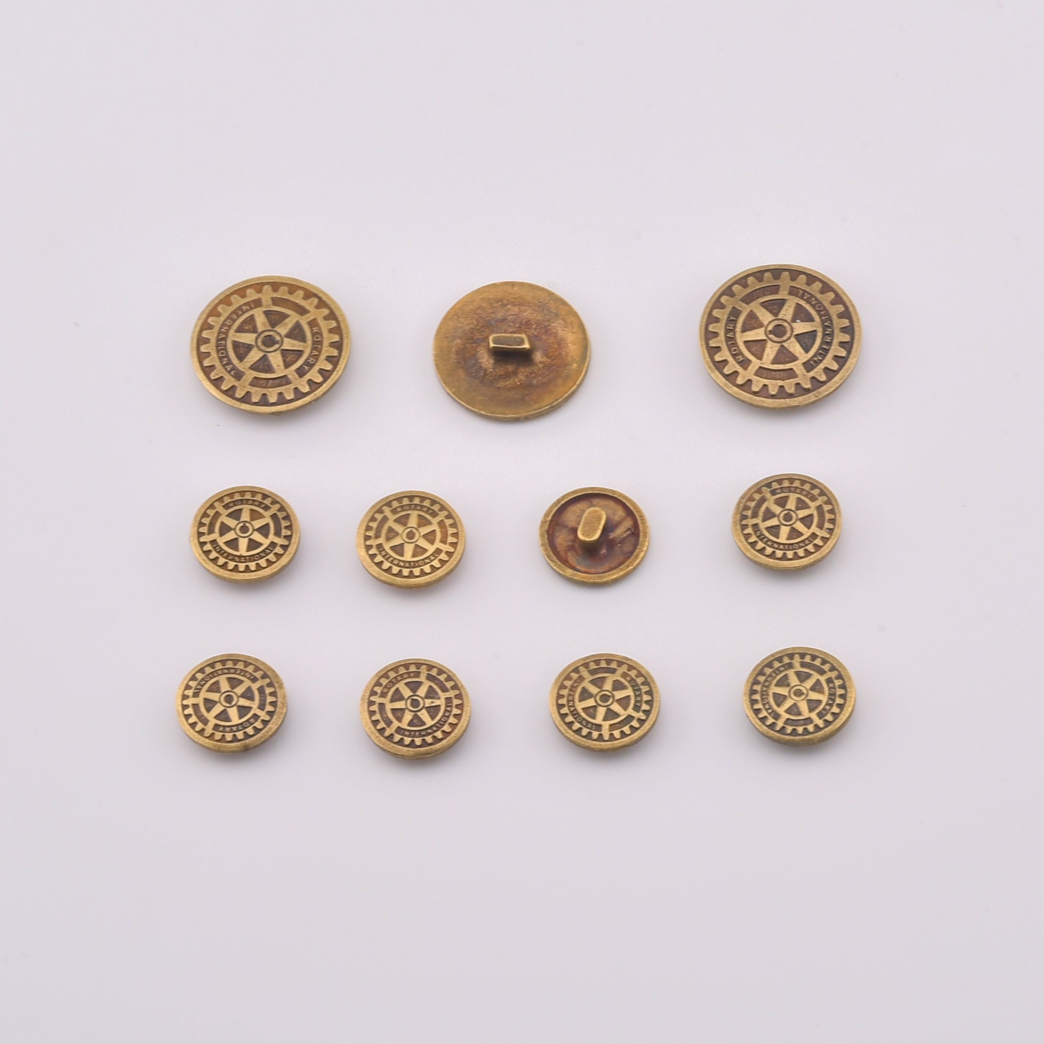 Set de 11 nasturi metalici pentru sacou, cu emblema Rotary in relief si finisaj din bronz.