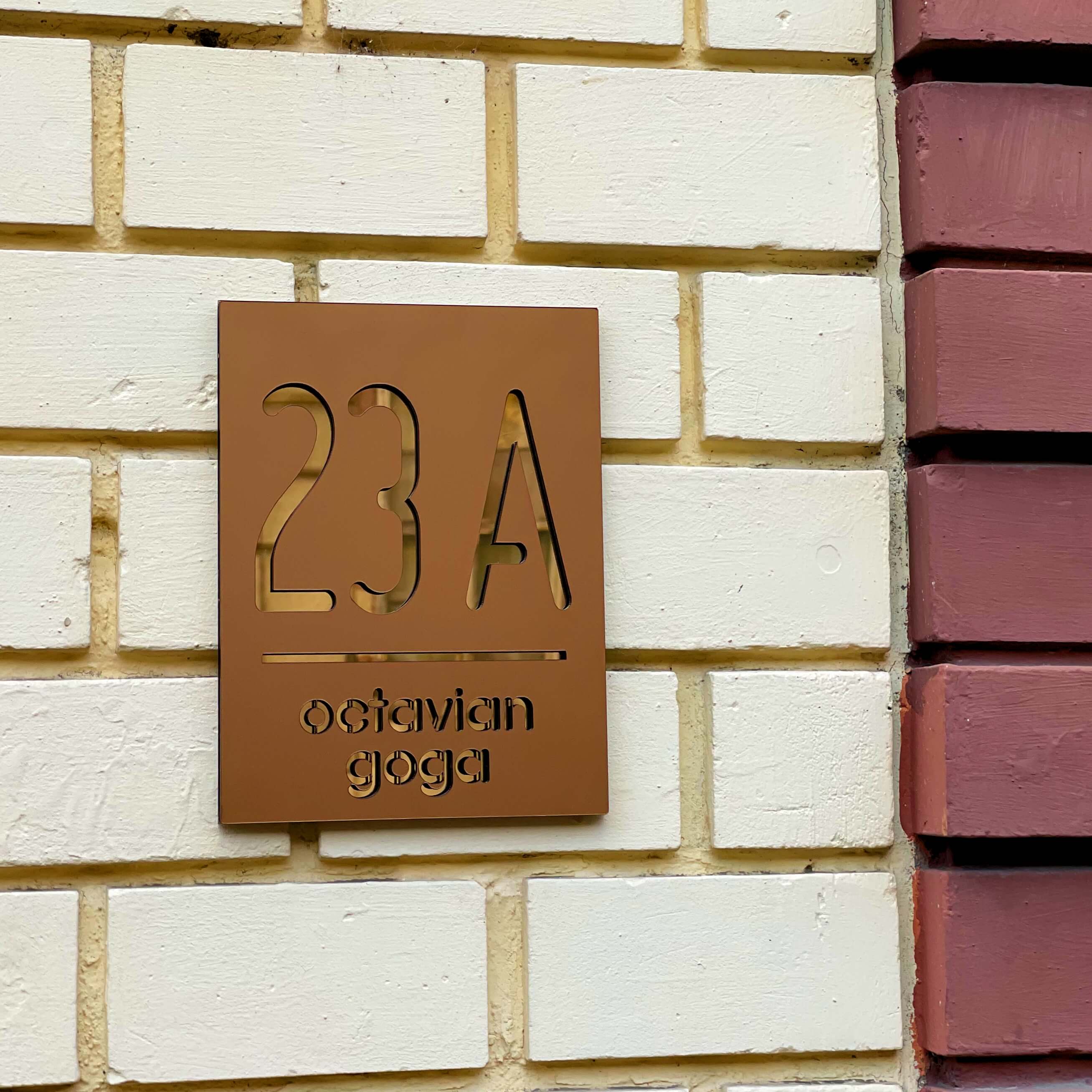 Imagine cu Numar Casa Bronz Auriu Oglinda pe un perete de caramida