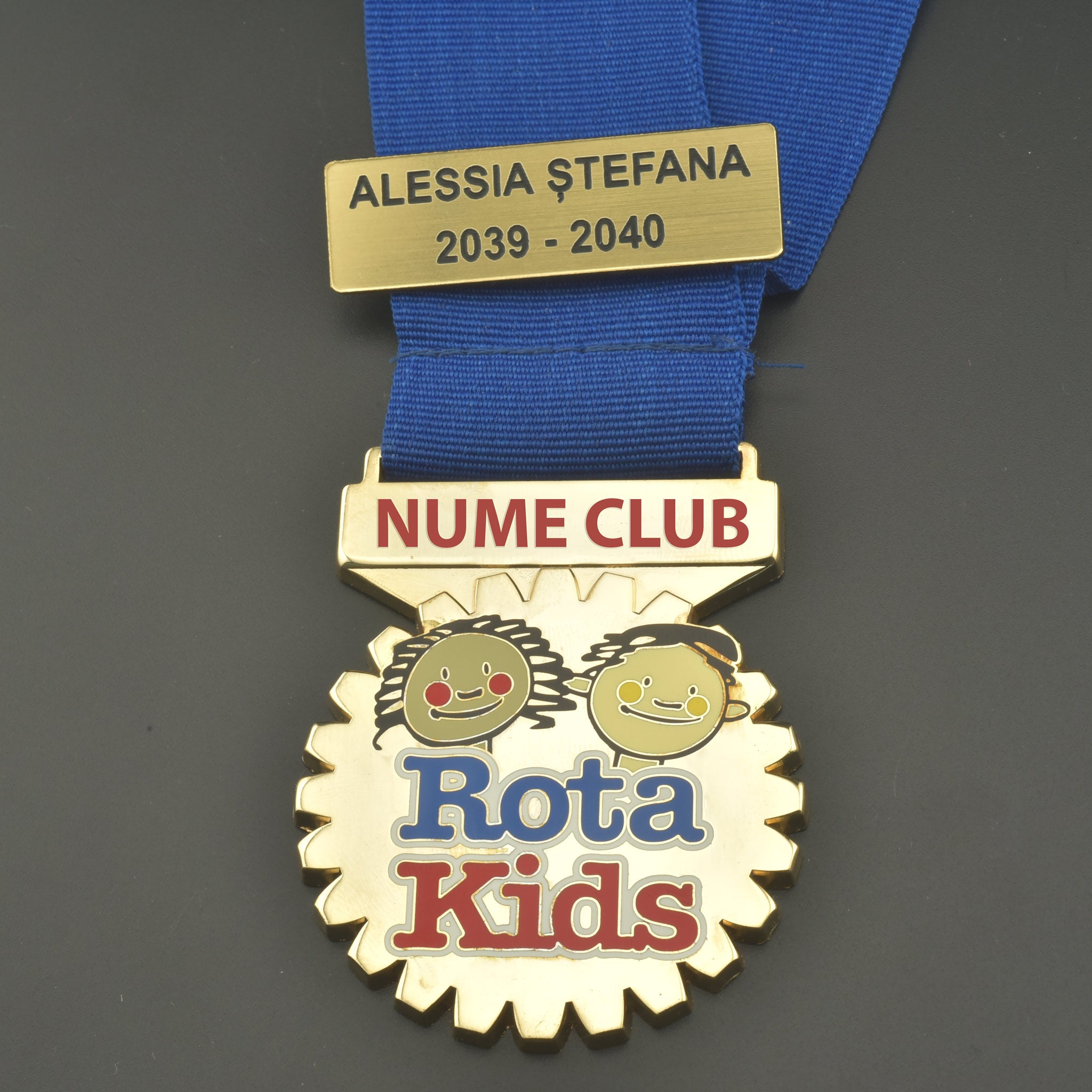 Colan circular gravat Rotakids, montat pe un suport textil albastru cu tricolor.