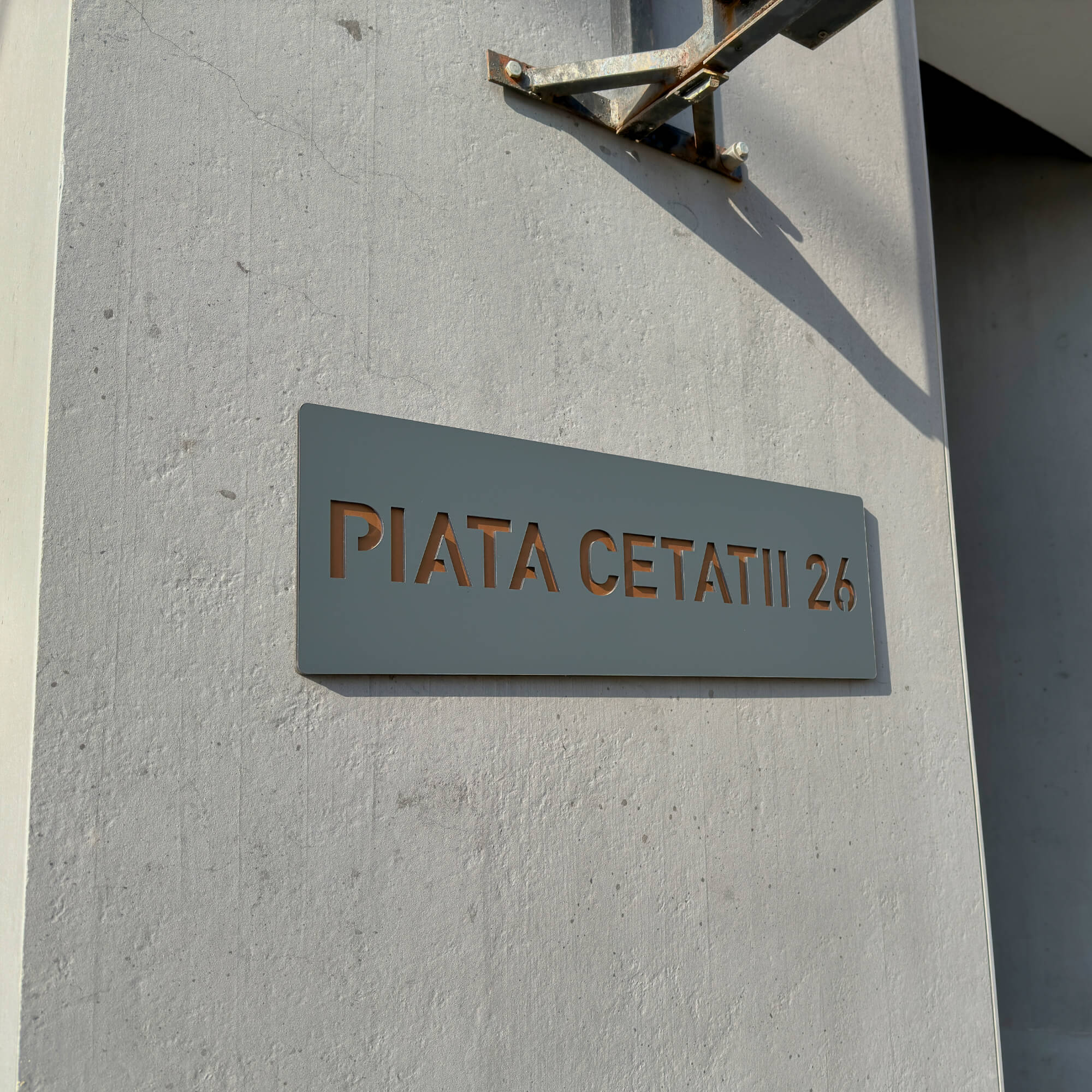 Imagine cu o placuta de casa din material acrilic de culoare gri antracit si bronz lucios montat pe un perete.