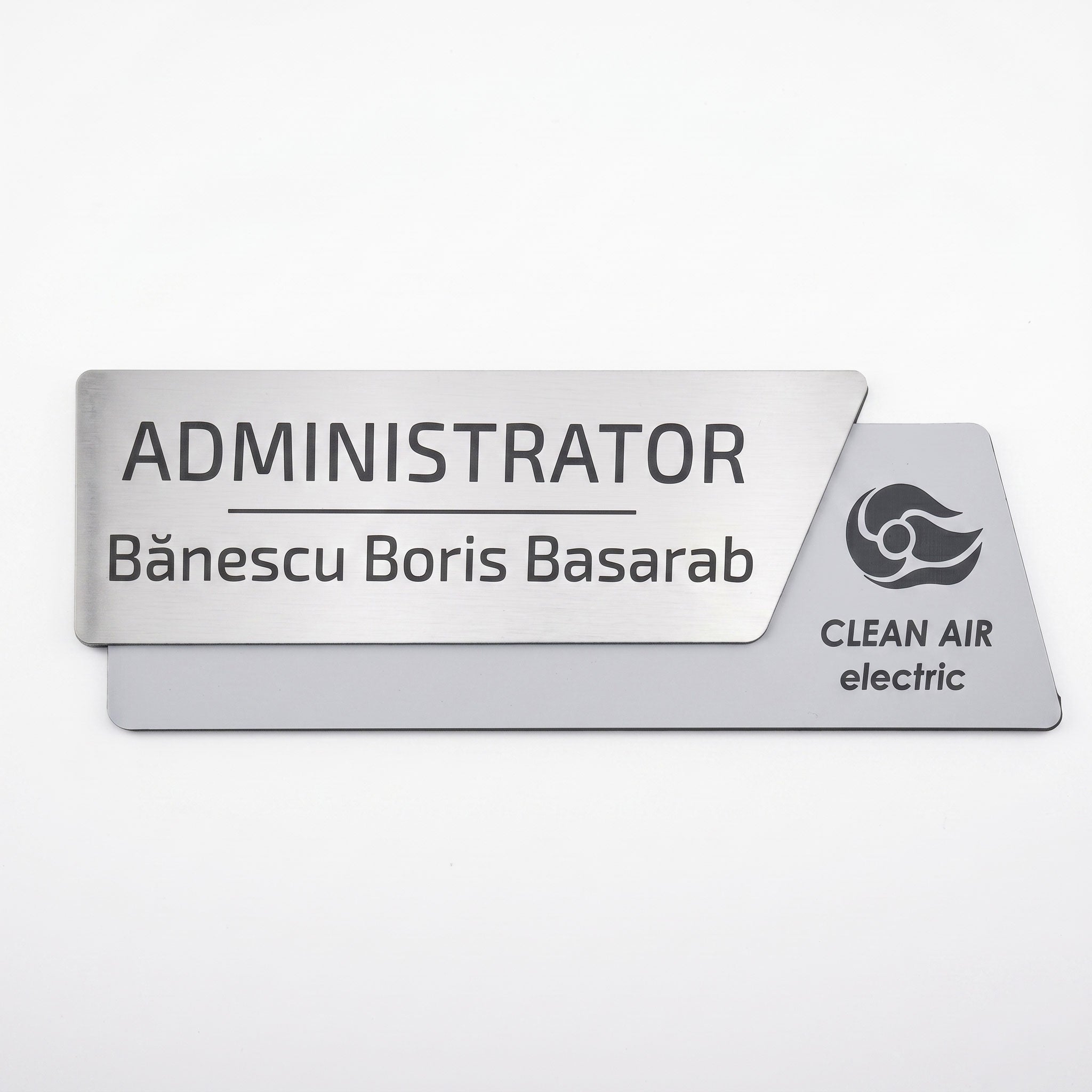 Plăcuță premium de identificare pentru birou formată din două elemente, cu fața metalică argintiu periat gravată cu textul „ADMINISTRATOR Bănescu Boris Basarab” și o bază asimetrică gri mat cu logo-ul Clean Air electric, pe fundal alb.