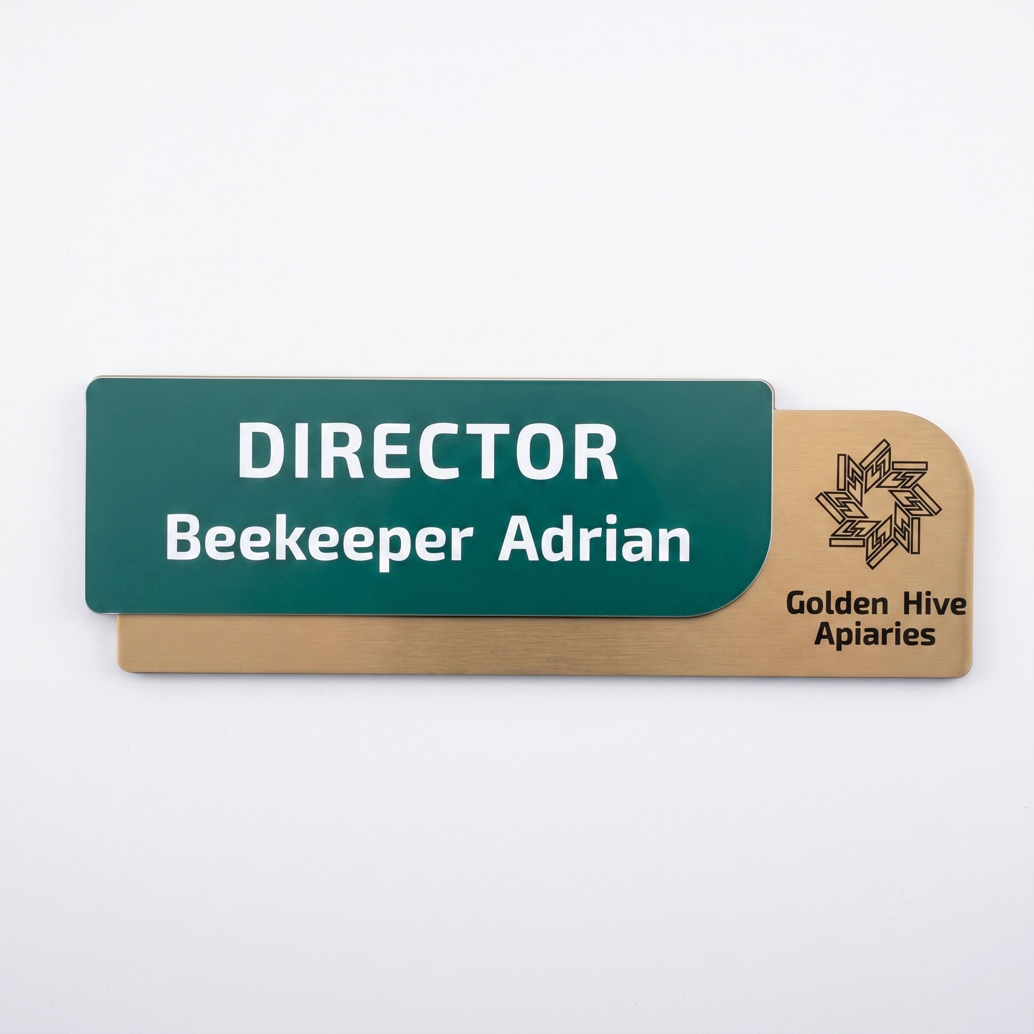 Plăcuță de identificare pentru birou formată din două elemente, cu fața verde închis text „DIRECTOR Beekeeper Adrian” și baza suport cu textură de lemn maro deschis și logo-ul Golden Hive Apiaries, pe fundal alb.