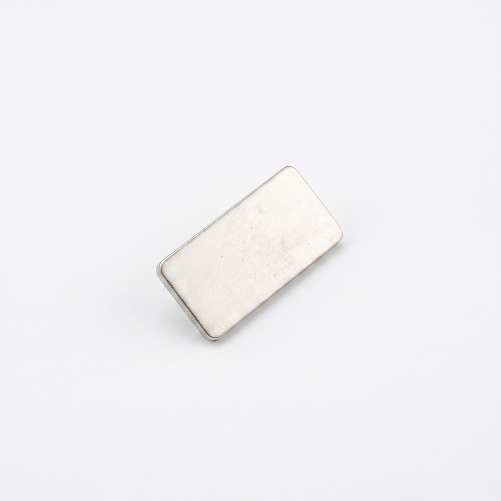 Insigna metalica personalizabila din gama silver cu forma dreptunghiulara si dimensiune de 2.5x1.2 cm, dotata cu ac de siguranta si clema fluture argintie.