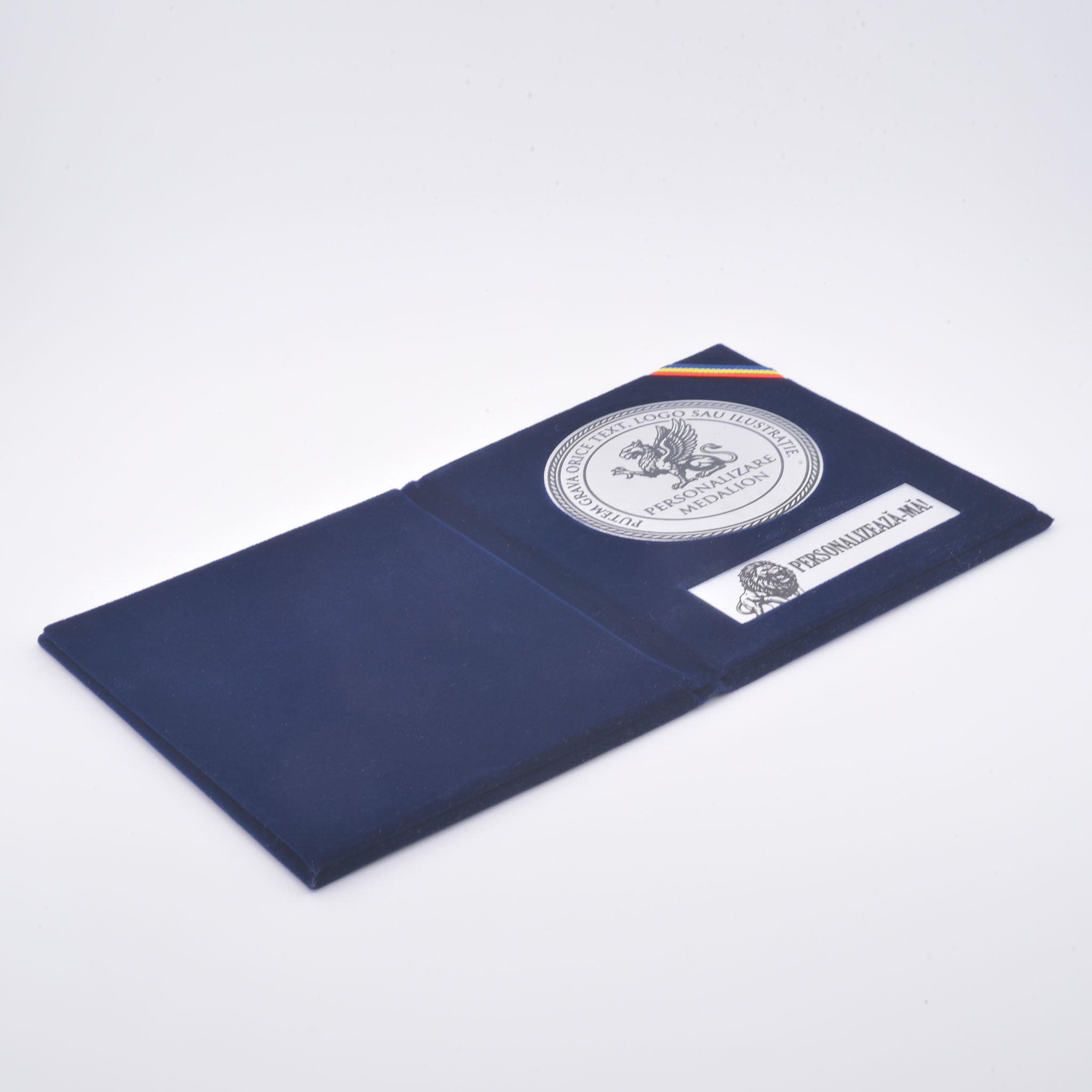 Medalie de 70 mm din argintiu periat și plăcuță personalizată prin gravură laser, montate în mapă slim din catifea albastru închis.