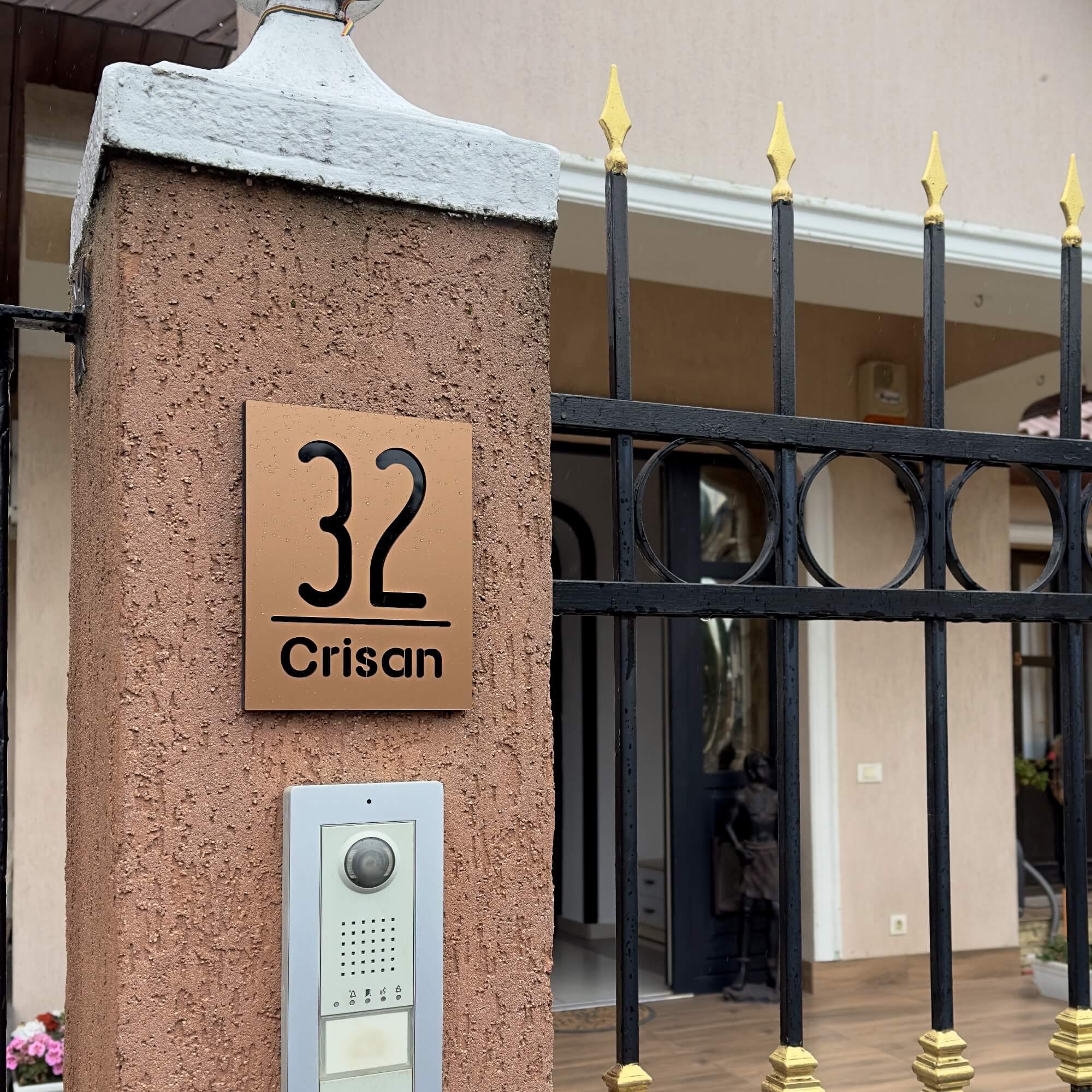 Imagine cu un numar casa bronz maro negru instalat pe un perete tencuit