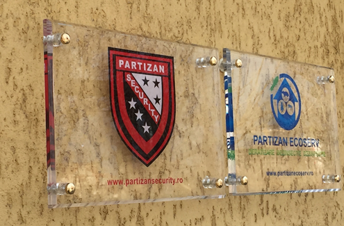 Placute de firma din plexiglass transparent montate una langa cealalta pe perete bej tencuit